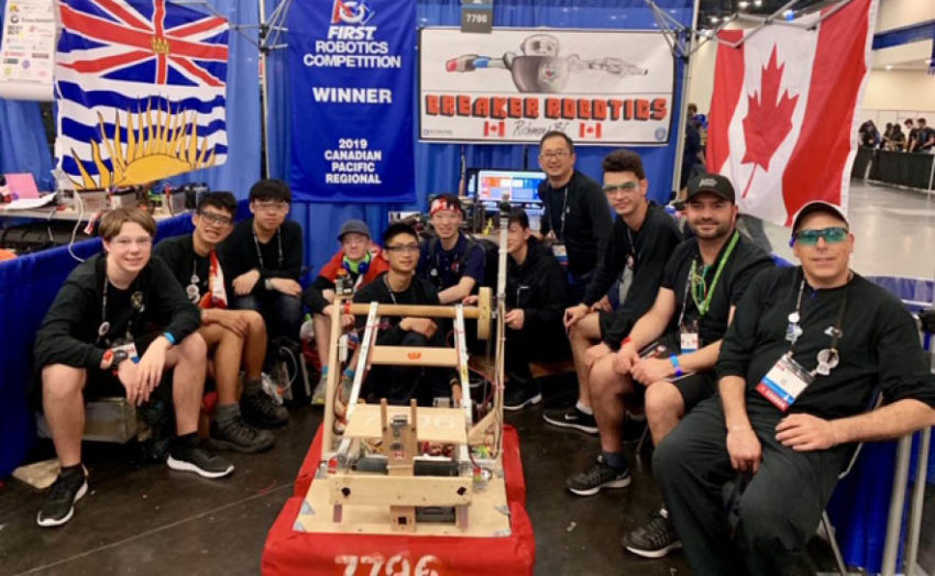 Image of robotics team standing around their wooden robot